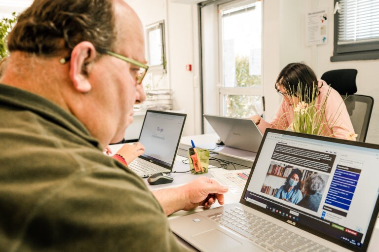 Photographie d'un transcripteur FALC réfléchissant devant un écran d'ordinateur.